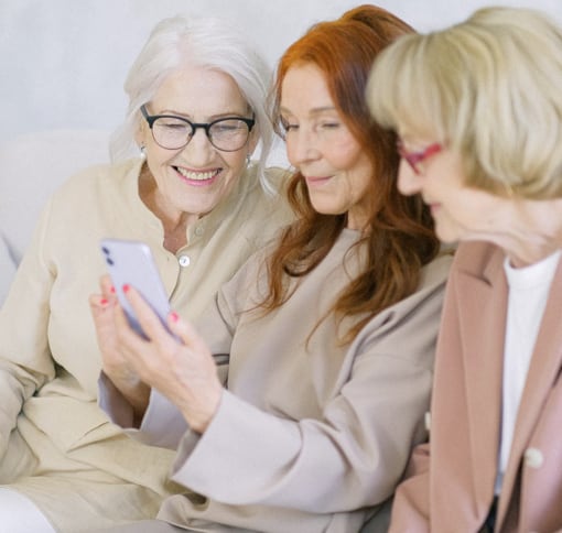 three women holding a mobile device during a videocall